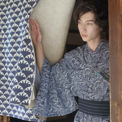 A man is dressed with Japanese Wave Pattern Kimono. Kimono material is cotton. a dark obi belt is hooked around his waist to close the men's kimono