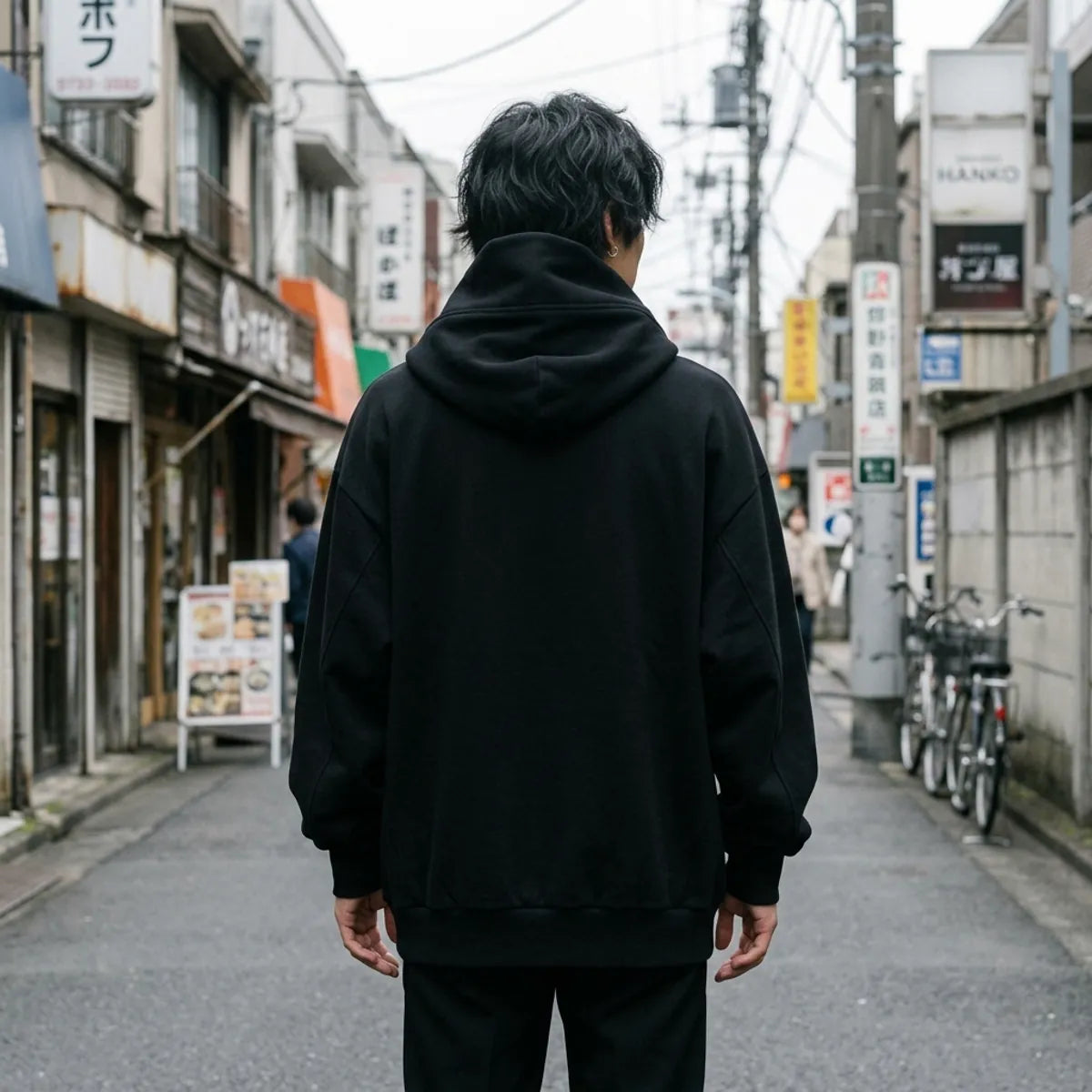 The back of the black funnel neck hoodie, plain black with the tall hood rising around the neck