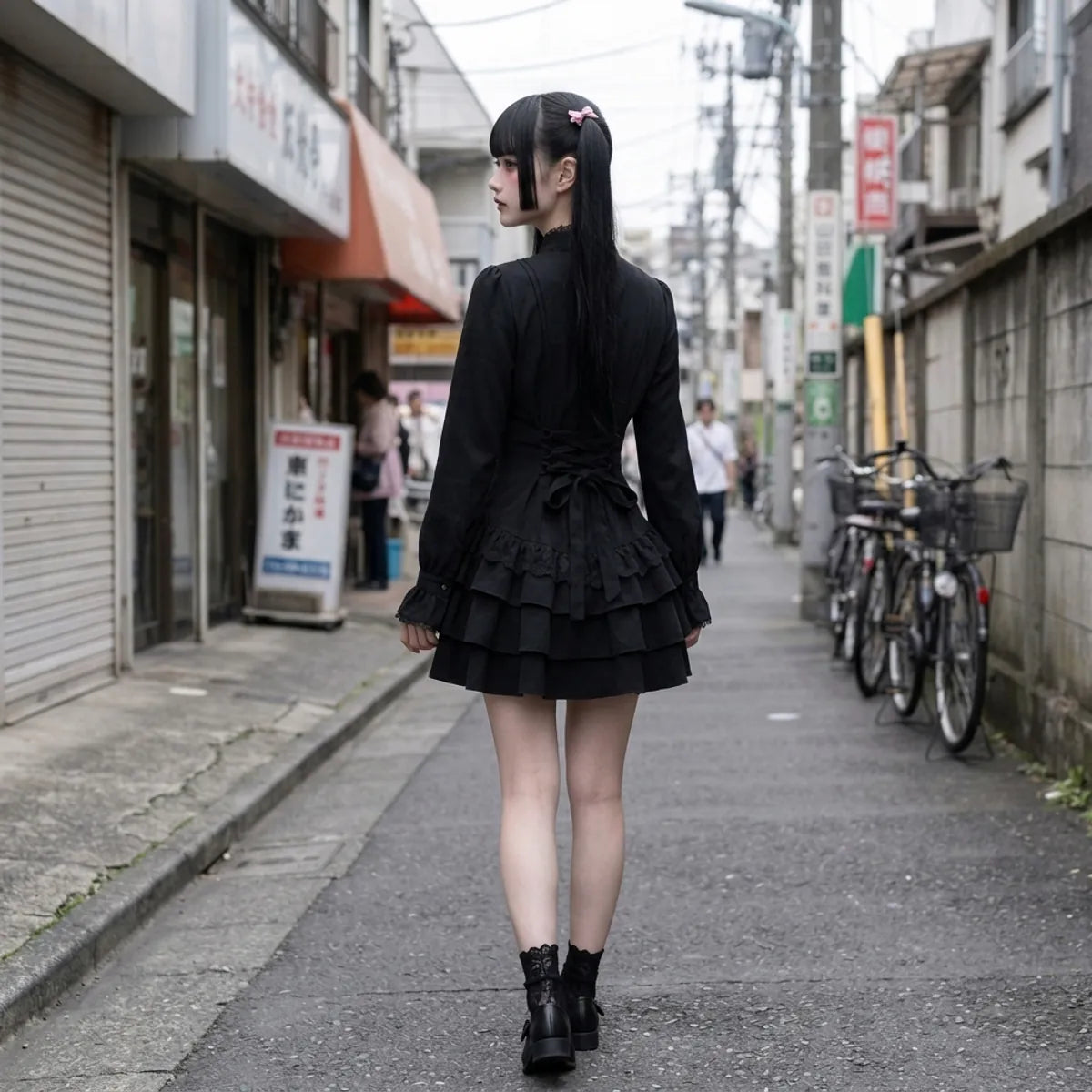 Back view of the black mini dress, the ribbon lacing at the waist and the two flounces of the skirt