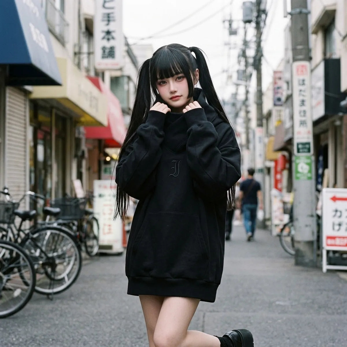 Black oversized hoodie worn by a woman in Harajuku, the chimney collar wrapped around her neck
