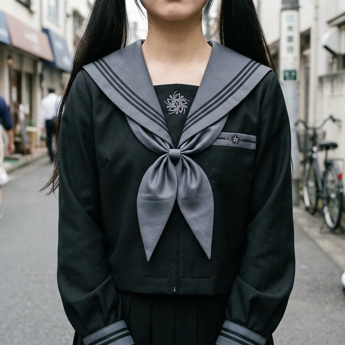 Close view of the grey sailor collar with black stripes, the grey scarf and the embroidered emblem