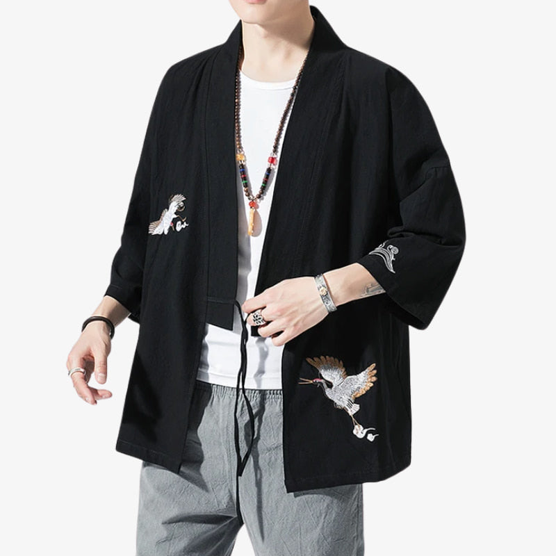 Person wearing a black embroidered jacket Haori Men over a white shirt on a white background