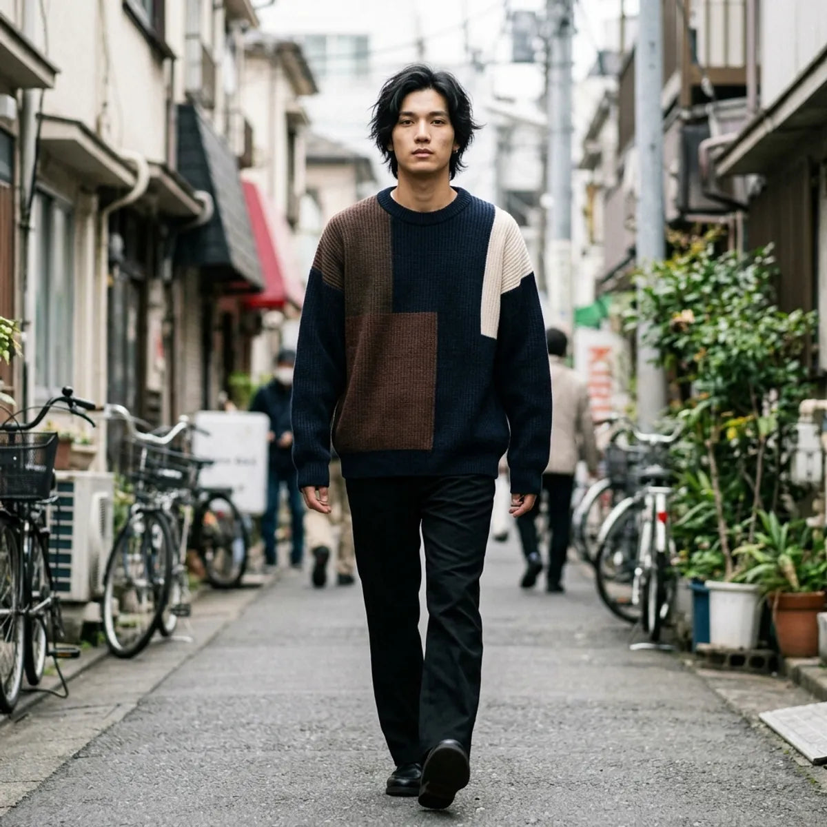 Model walking in a navy patchwork knit pullover with chunky ribbed cuffs