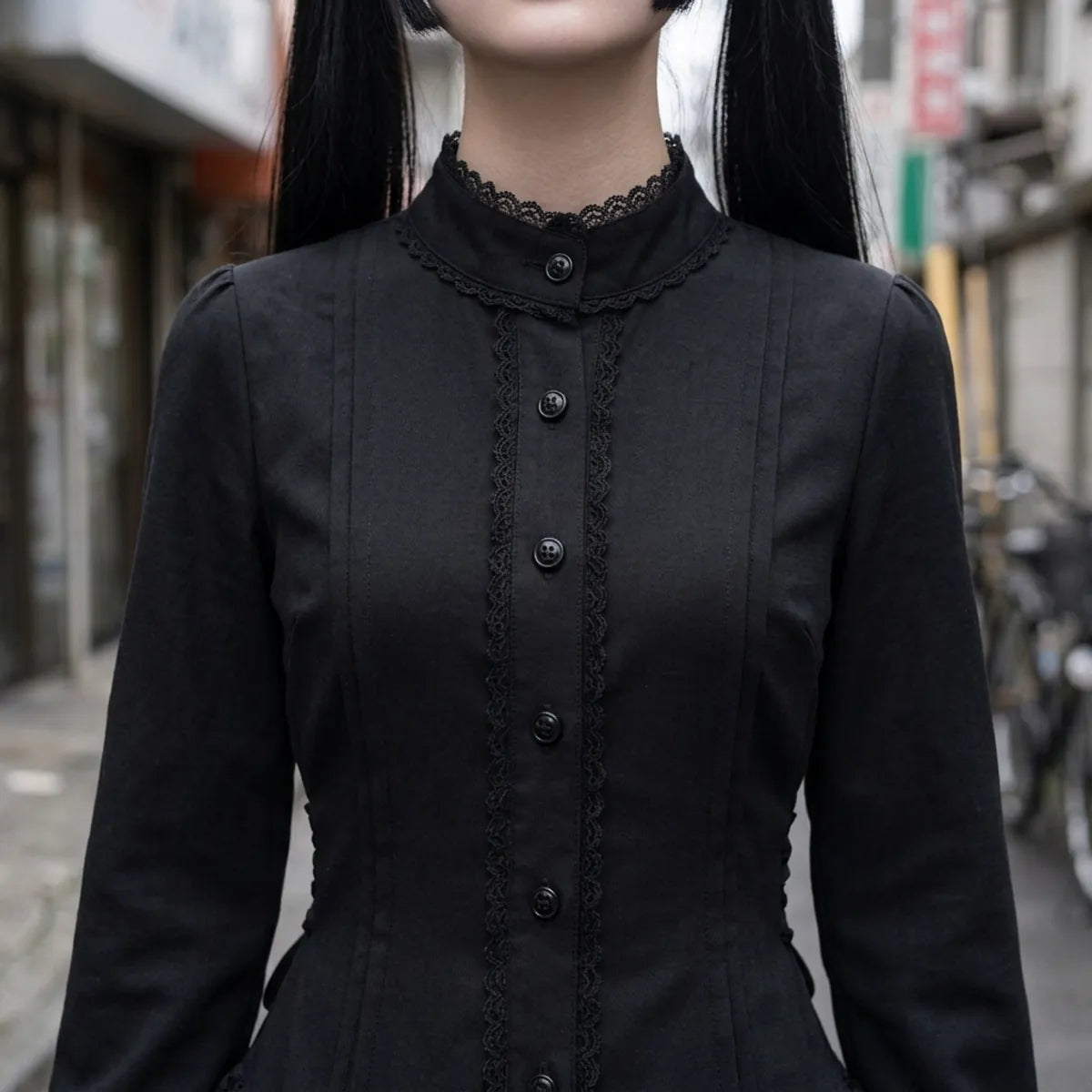 Close view of the stand collar, the black lace edging and the row of buttons on the bodice