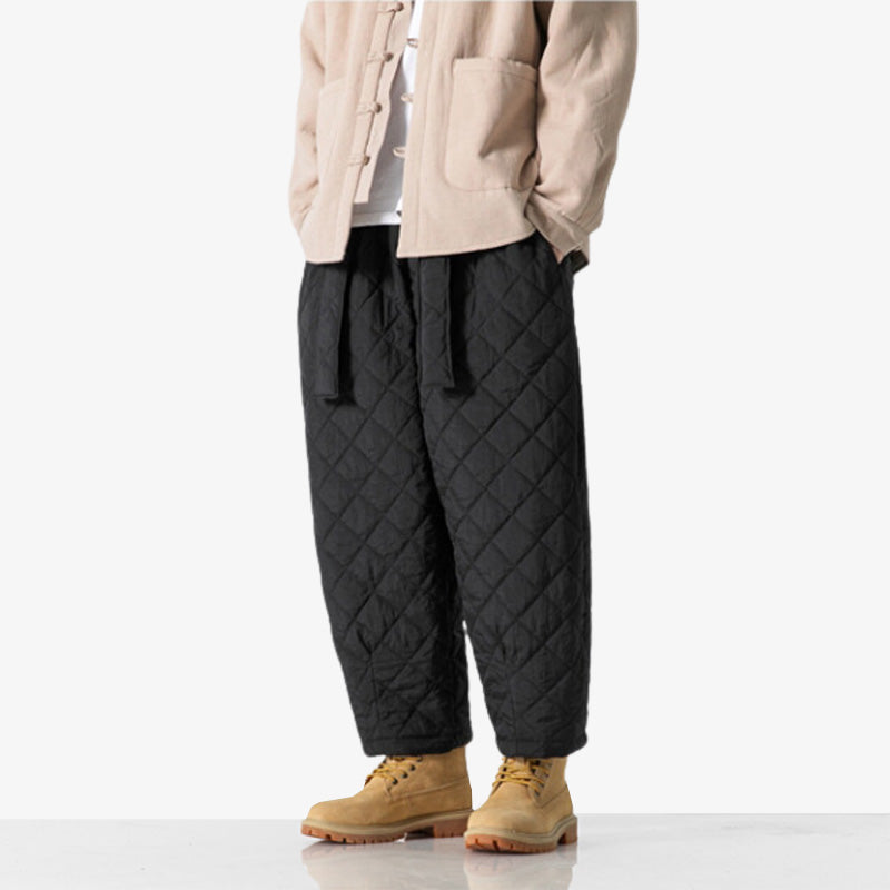 A man stands wearing black Japanese cargo pants mens, a beige jacket and Timberland mountain boots.