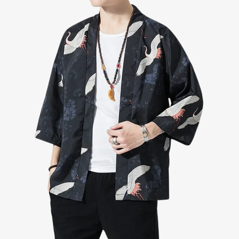 Person wearing a black japanese kimono jacket mens with crane patterns on a white background