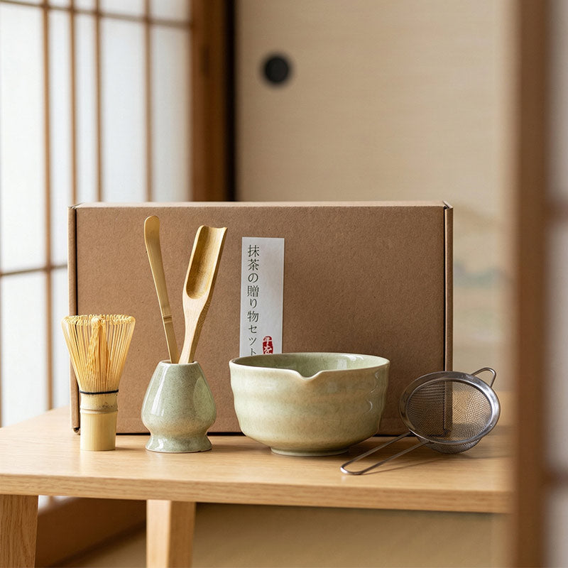 Tea-making set with a bowl, whisk, and other tools on a wooden table.