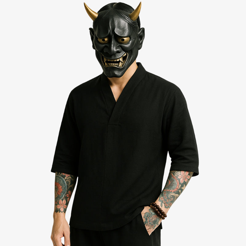 Person wearing a black Japanese demon mask and japanese v-neck shirt with Irezumi tattoos visible on arms.