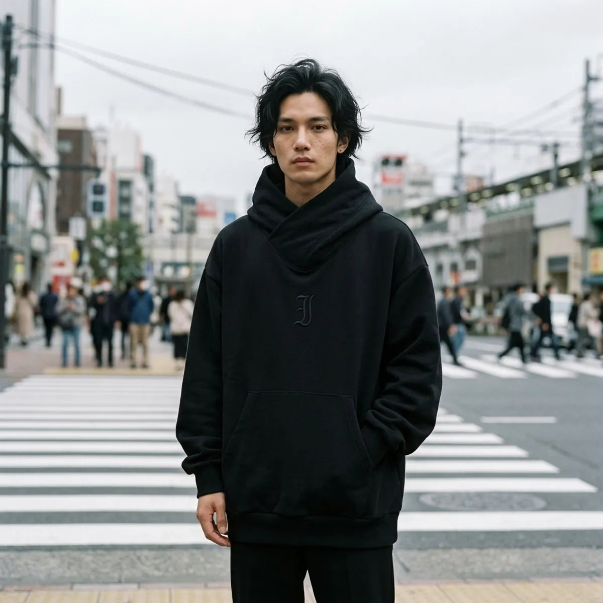Oversized black sweatshirt with a wrap collar worn at a pedestrian crossing in Tokyo on a grey day