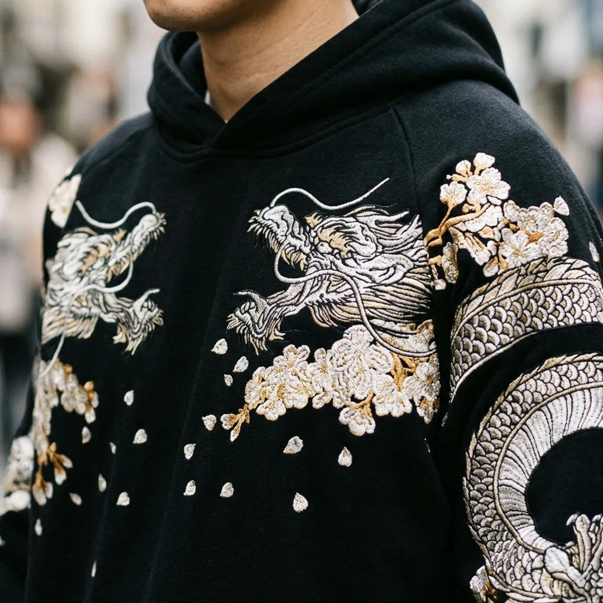 Close view of the silver dragon and cherry blossom embroidery on the chest and shoulder of the hoodie