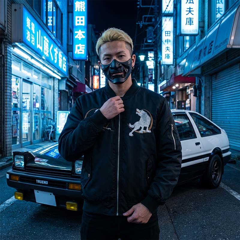 Person wearing a black Sukajan jacket with a wolf emblem emboirederd in an urban Japanese street with neon signs and a vintage trueno car
