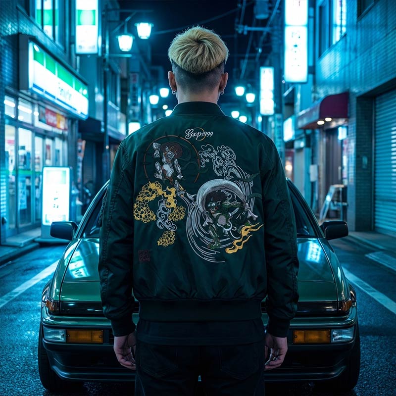 Person wearing a dark sukajan tailor toyo jacket with a colorful Japanese design on the back, standing in front of a car in an Harajuku street at night.