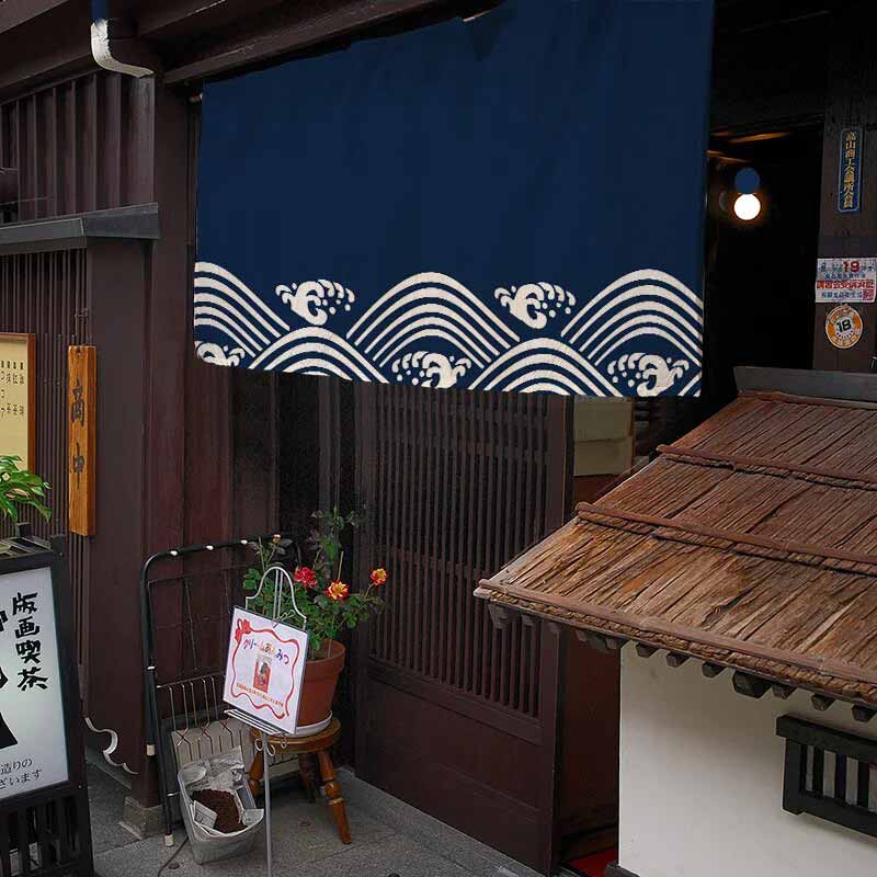 Traditional Japanese establishment with a blue wave curtain and wooden architecture.