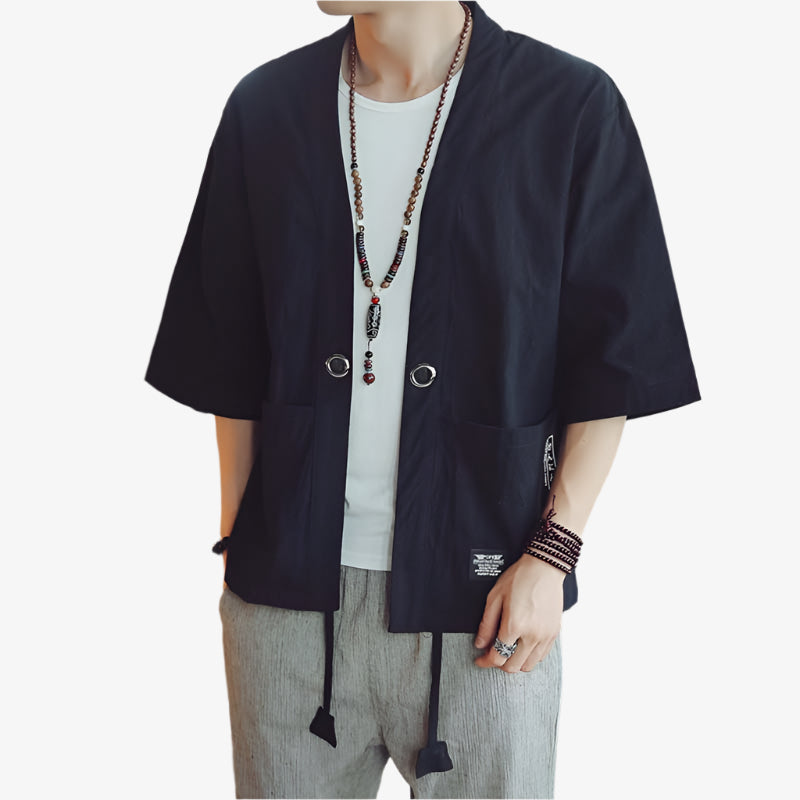 Person wearing a black haori kimono-me Japanese over a white shirt in an indoor setting