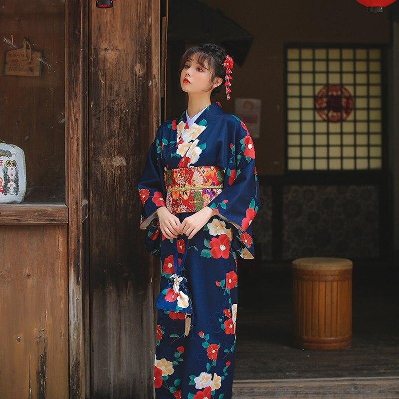 apanese long kimono robe adorned with beautiful floral prints. The woman is standing, her kimono secured with an Obi belt, and a Kanzashi in her hair