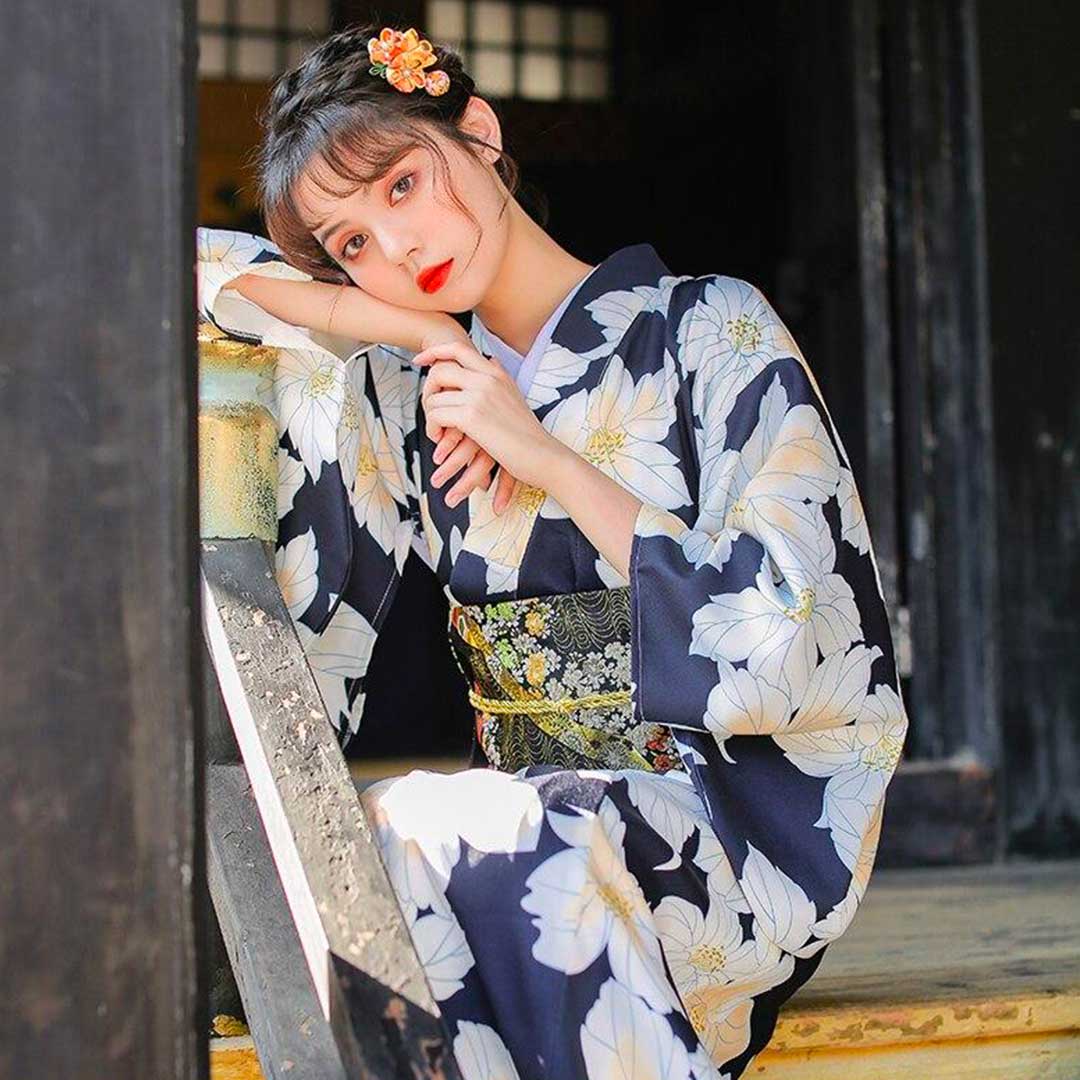 apanese robe kimono adorned with yellow flower designs. A woman stands gracefully, wearing a yellow flower kanzashi in her hair.