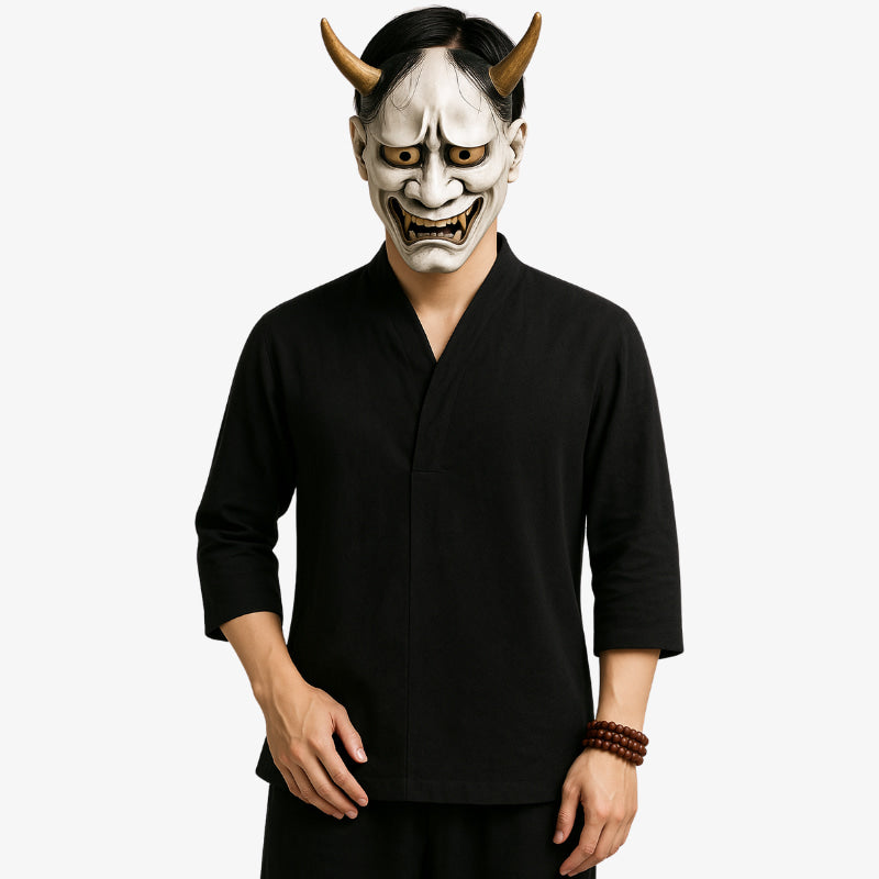 Person wearing a Hannya mask and black Japanese shirt zen outfit on a white background