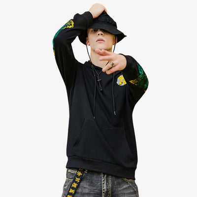 Person wearing a Japanese hoodie black with colorful designs on sleeves and a hat, against a white background
