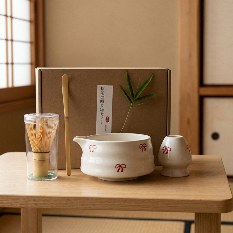 A japanese Matcha Tea set with a glass container, wooden spoon, and ceramic bowls on a wooden table.