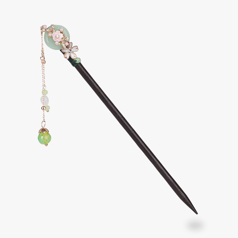 A Kanzashi sakura hair pick with cherry blossoms inlaid on the wood of the stick. Pearls from the hair jewellery hang from the end of the jewelry at the end of a chain.
