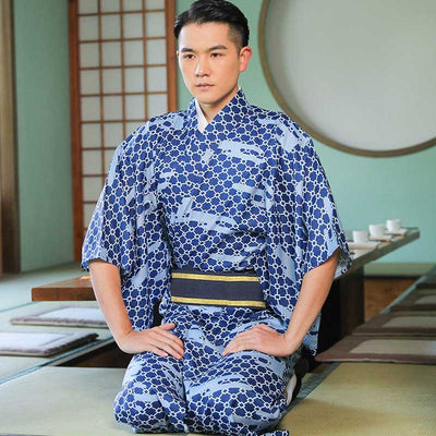 A Japanese man is seated and dressed in a traditional kimono robes for men. He sit in a traditional japanese tea house