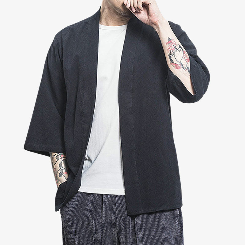 A man is wearing a black Japanese cardigan kimono jacket. The material is linen and cotton. It is a plain Japanese garment