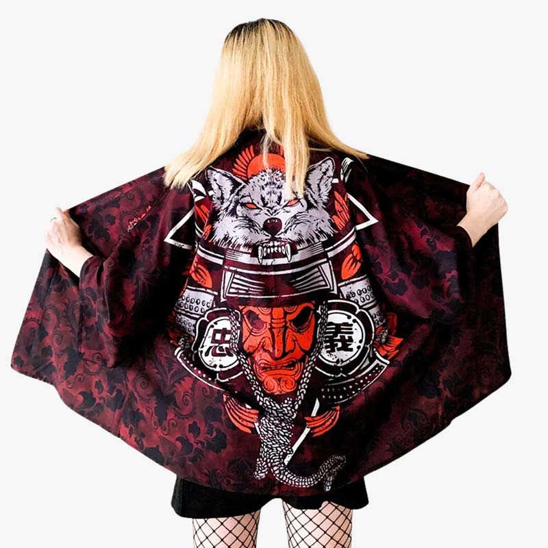 A woman wearing a red Onna Bugeisha Kimono jacket with a graphic design, including a red Oni samurai mask and helmet, on a black background.