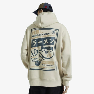 Person wearing a beige Tokyo Japan Hoodie with a graphic design on the back, featuring text and a fish illustration.