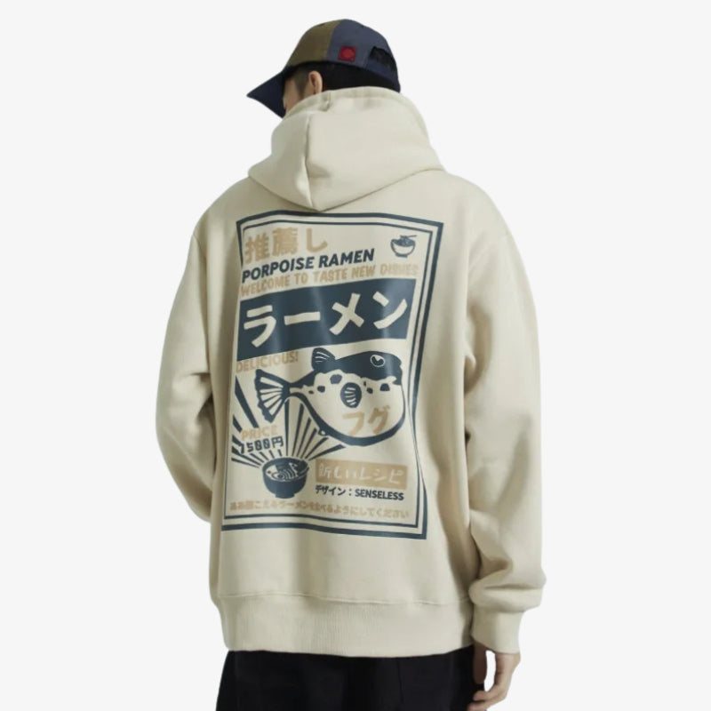 Person wearing a beige Tokyo Japan Hoodie with a graphic design on the back, featuring text and a fish illustration.