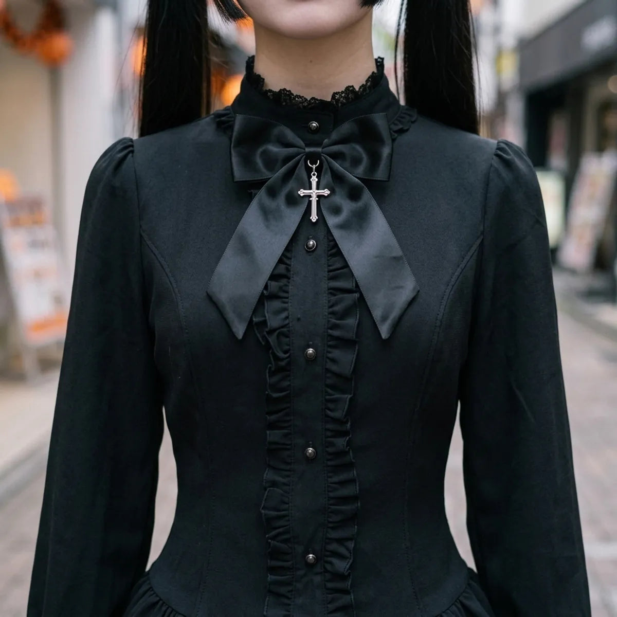 Close view of the stand collar, the satin bow with its silver cross and the buttoned ruffled placket
