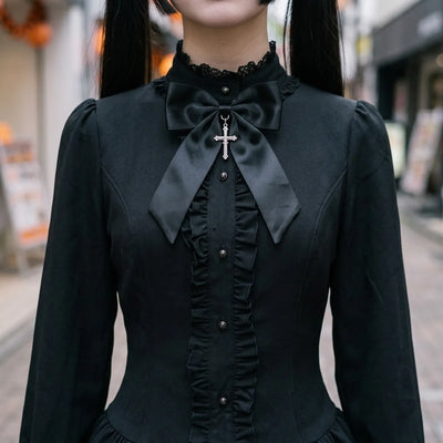 Close view of the stand collar, the satin bow with its silver cross and the buttoned ruffled placket