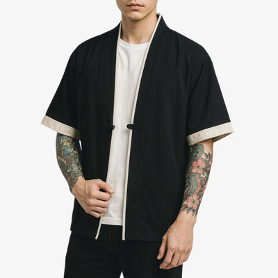 Person wearing a black kimono kimono style jacket with white trim on a white background