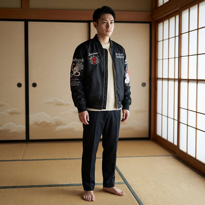 Man wearing a black bomber jacket with white text and graphics in a traditional Japanese room.