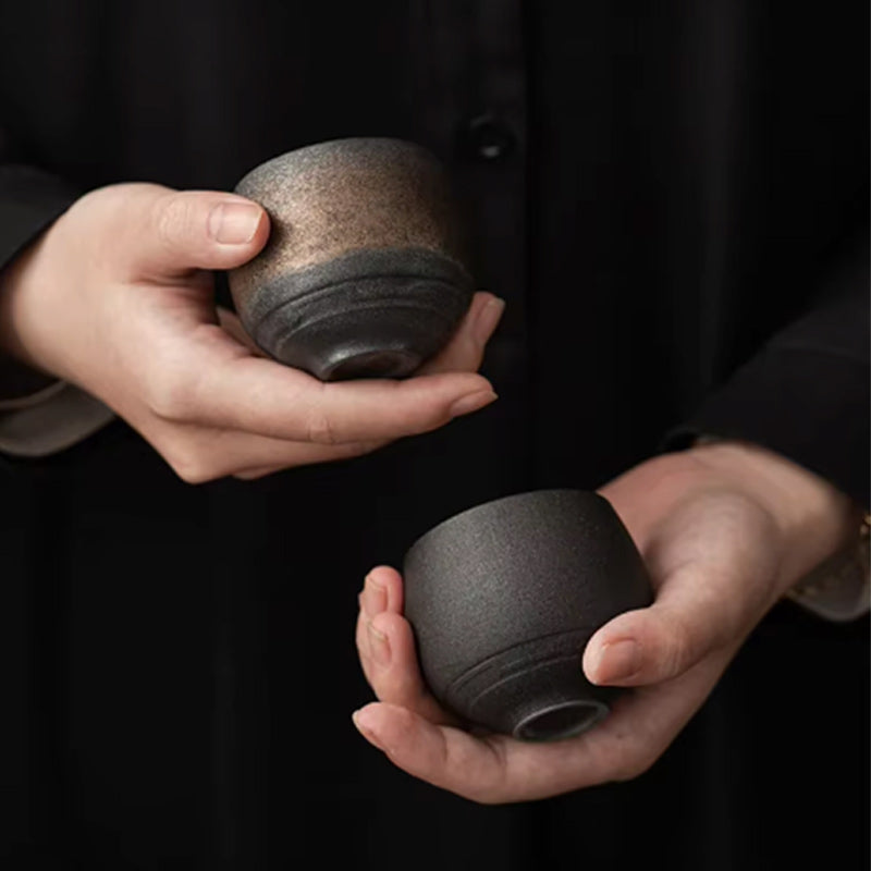 a man with black clothes holds two ceramic matcha cups featuring high-quality craftsmanship, perfect for elevating your Japanese tea experience