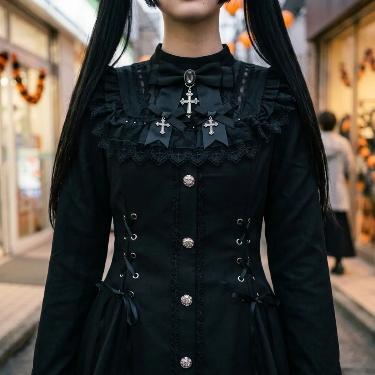 Close view of the corset lacing, the silver buttons and the black lace collar with cross motifs