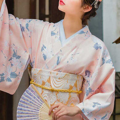 a japanese woman is dressed with a corset obi belt to hold her white kimono printed with  japanese symbols