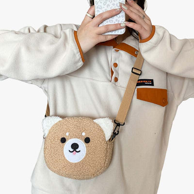 a woman takes a photo with her phone. She is wearing a sweater and a crossbody kawaii bag with teddy bear-shaped. The crossbody Japanese bag is your go-to accessory for carrying essentials in a fun and stylish way, featuring vibrant colors and cute design