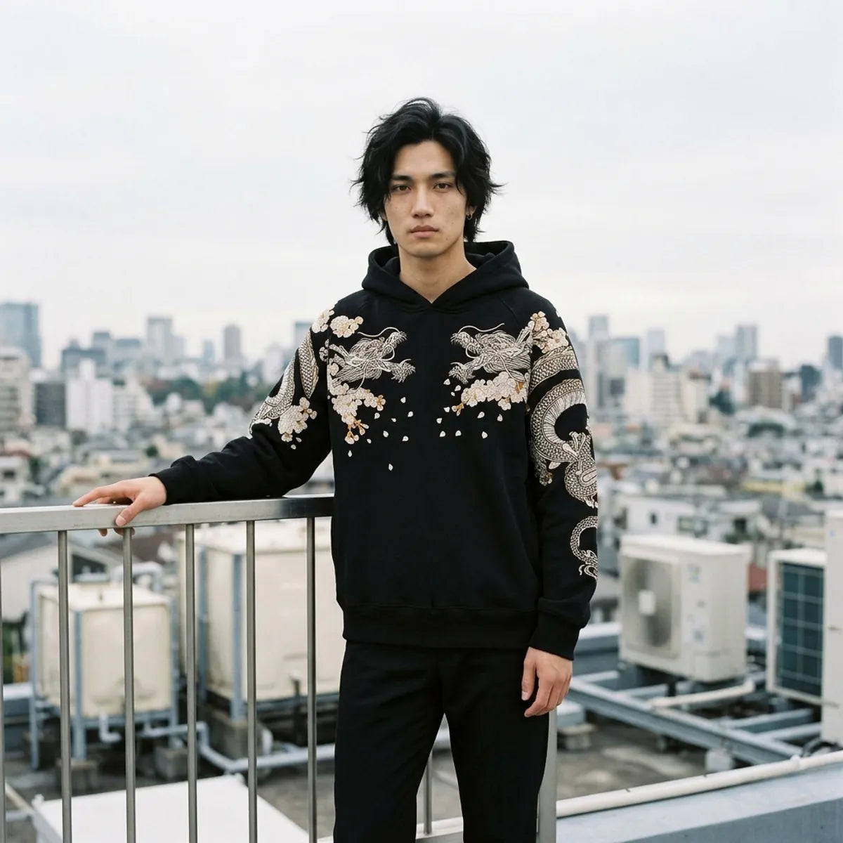 The embroidered dragon hoodie worn on a Tokyo rooftop at the end of the afternoon, the city behind