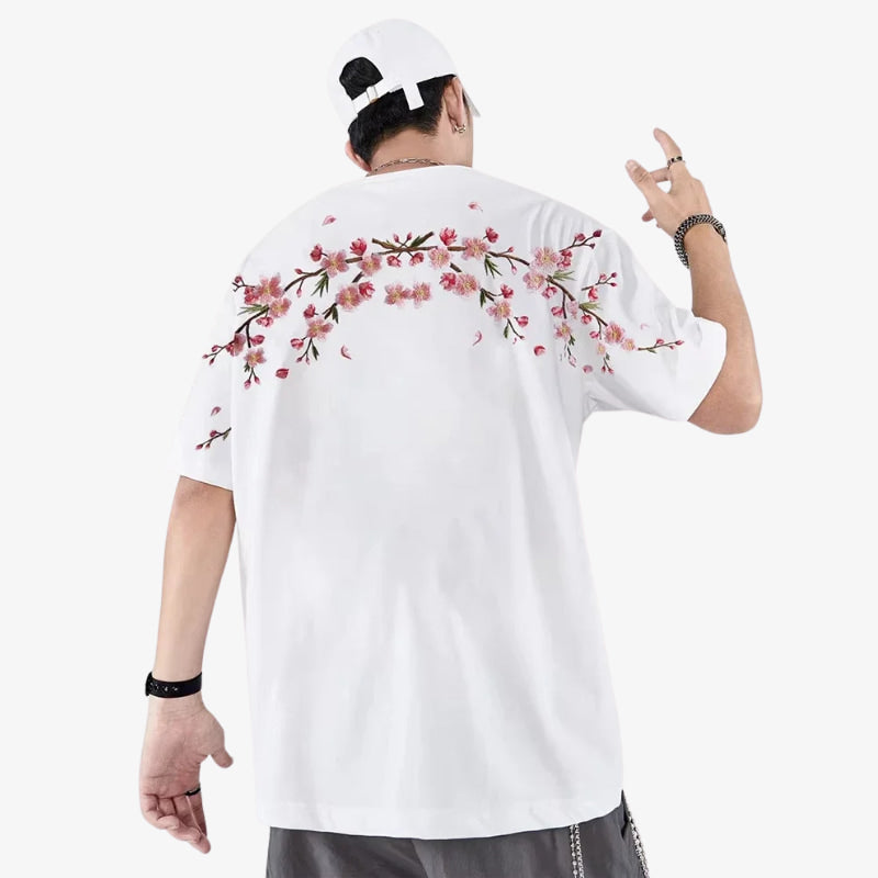 Person wearing a white floral embroidered shirt with floral designs on the back, posing against a white background.