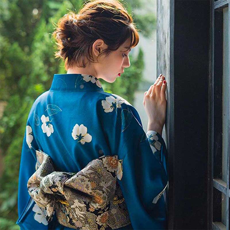 Flower Japanese kimono dress worn by a woman, featuring traditional floral motifs. The intricate flower designs enhance the elegance of the traditional japanese clothe. The woman also wear a japanese obi belt above her kimono