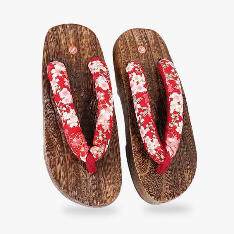 A pair of wooden Geisha sandals, intricately designed for the art of geisha appearances. The straps are red and printed with white japanese flowers