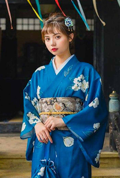 Japanese traditional kimono dress in blue, adorned with delicate flower motifs. A woman is gracefully dressed in this classic attire, highlighting the beautiful floral patterns."