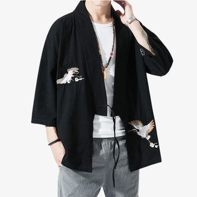 Person wearing a black kimono Haori for Men with Japaense bird embroidery on a white background. This Japanese symboles is named a crane