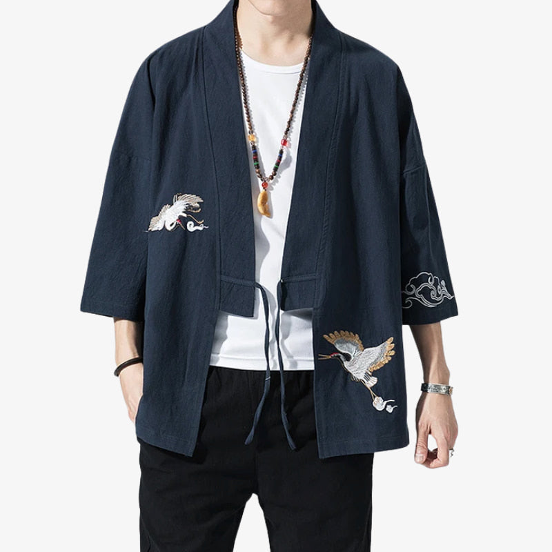 Person wearing a dark blue kimono Haori jacket for mens with embroidered Japanese cranes Tsuru designs on a white background