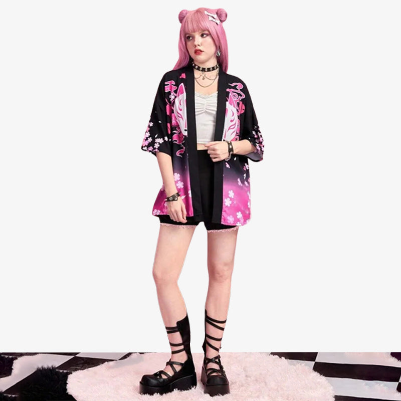 A woman is dressed with black Haori kimono for women, inspired by traditional pattern as the white kitsune fox mask and the japanese blossom flowers (sakura). The haori jacket is crafted with a kawaii style outfit