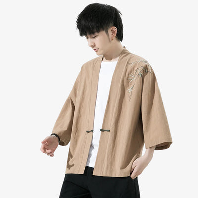Person wearing a beige haori kimon jacket style jacket with floral embroidery on a white background