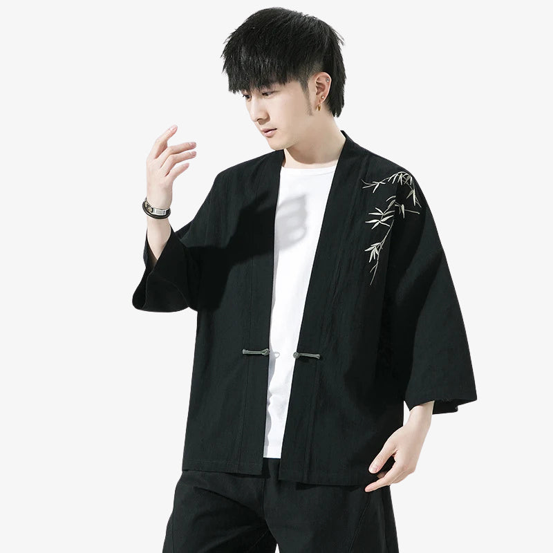 Person wearing a black haori kimono men style jacket with white bamboo embroidery on a white background
