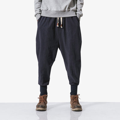 A man is dressed with Harajuku pants, a grey sweatshirt and ankle boots. The bottom of the Japanese trousers is tight