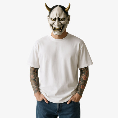 a man is dressed with a white japanese Harajuku Lovers Shirt. His face is hide by a hannya traditional mask. He has irezumi tattoo on harms