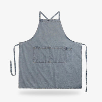 Japanese apron denim style crafted from high-quality blue denim, designed with crossed straps and a front pocket for functional wear.